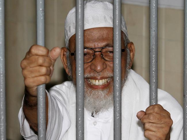 Radical Muslim cleric Abu Bakar Bashir smiles as he speaks to reporters from inside a holding cell while waiting for the start of his trial at a district court in Jakarta, Indonesia, Monday, March 14, 2011. Bashir who was allegedly helped fund and recruit foot-soldiers for a new al-Qaida-styled terror cell, faces a maximum penalty of death if found guilty. (AP Photo/Irwin Fedriansyah)