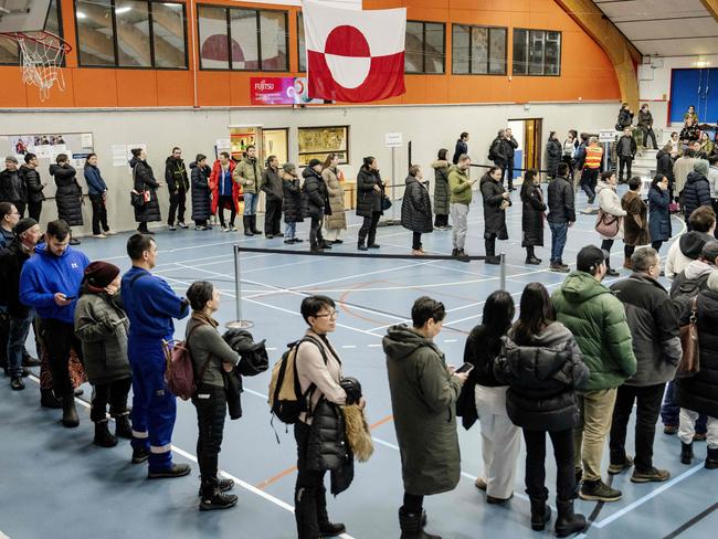 A flag with Greenland national colors is seen as people queue to vote at the polling station Godthaabshallen in Nuuk, Greenland, on March 11, 2025, on the day of Greenland, the autonomous Danish territory legislative elections. 31 members are to be elected to Inatsisartut, which is the Greenlandic parliament based in Greenland's capital, Nuuk. (Photo by Mads Claus Rasmussen / Ritzau Scanpix / AFP) / Denmark OUT