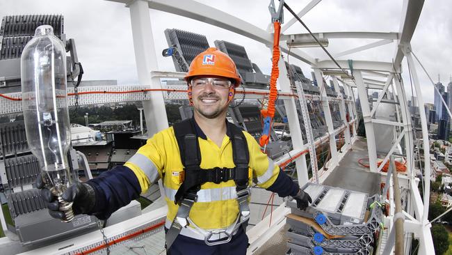 Nilsen electrician Daniel Creaco holds onto one of the old bulbs being replaced by the LED stacks beside him at the top of Light Tower 1. Picture: David Caird