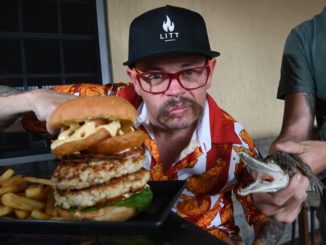 Australia’s #1 professional eater Cal Stubbs with the Berry Springs Tavern’s giant croc burger – and a friendly baby saltie. Picture: Katrina Bridgeford.