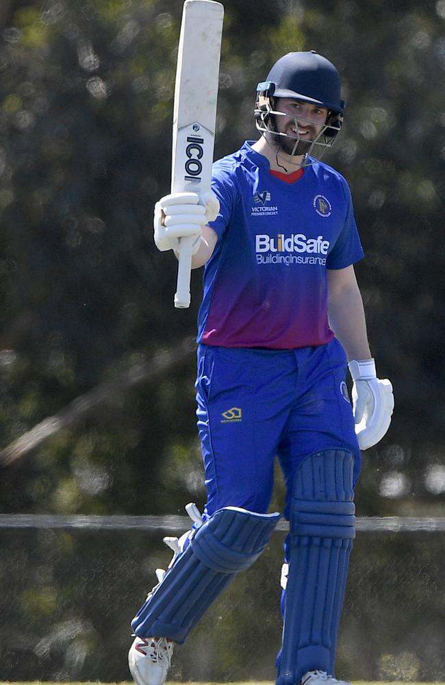 Liam Tomkin raises his bat after reaching 50.