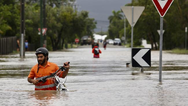 A resident pushes a bicycle through floodwaters in Hermit Park, Townsville, Sunday, February 3, 2019. Picture: AAP/Andrew Rankin