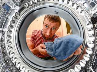 Man Doing Laundry Reaching Inside Washing Machine, inside view. Picture: Smoczyslaw