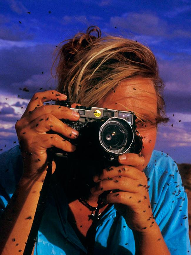 Autio taking photographs while covered in flies in the outback.