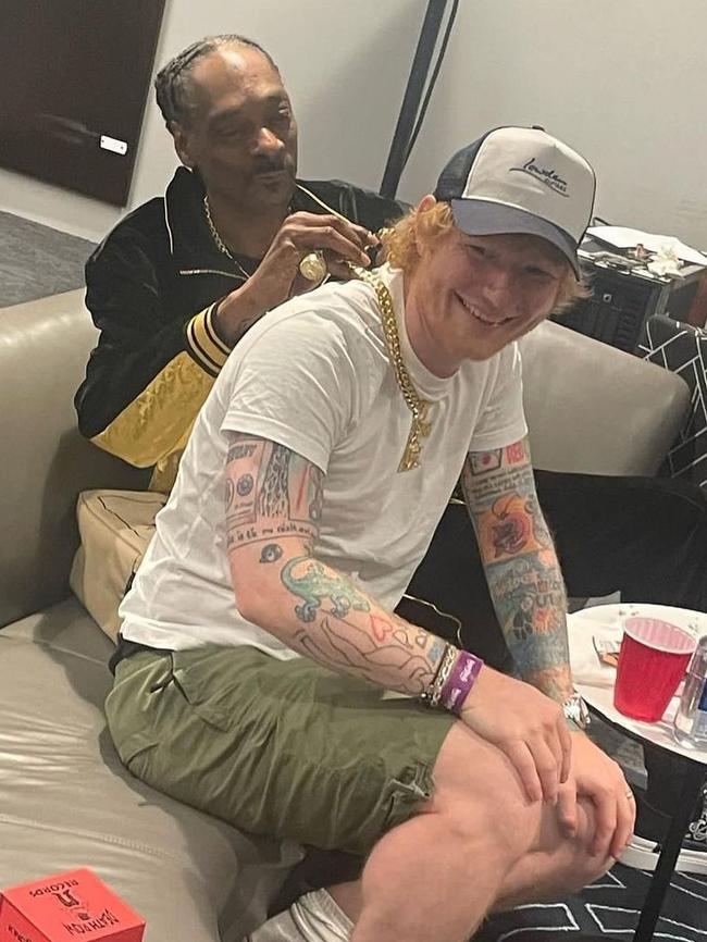 Snoop helps Sheeran clasp up a gold chain in his backstage lair.