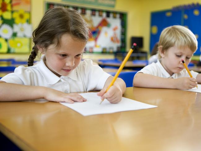 A pair of cute 5 year-old primary school children working hard on their studies in the classroom.