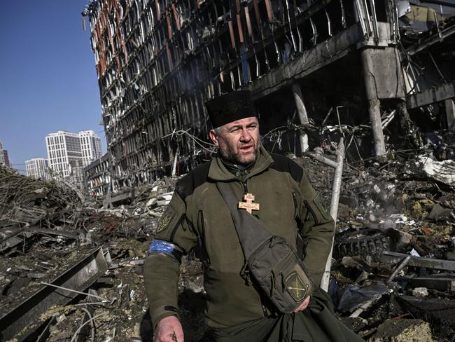 Ukraine army Chaplain Mikola Madenski walks through debris outside the destroyed Retroville shopping mall after a Russian attack on the Ukrainian capital Kyiv. Picture: Aris Messinis/AFP