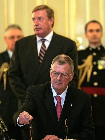 New Governor of Tasmania Peter Underwood signs documents at his swearing in ceremony at Government House in 2008, with former premier Paul Lennon behind.