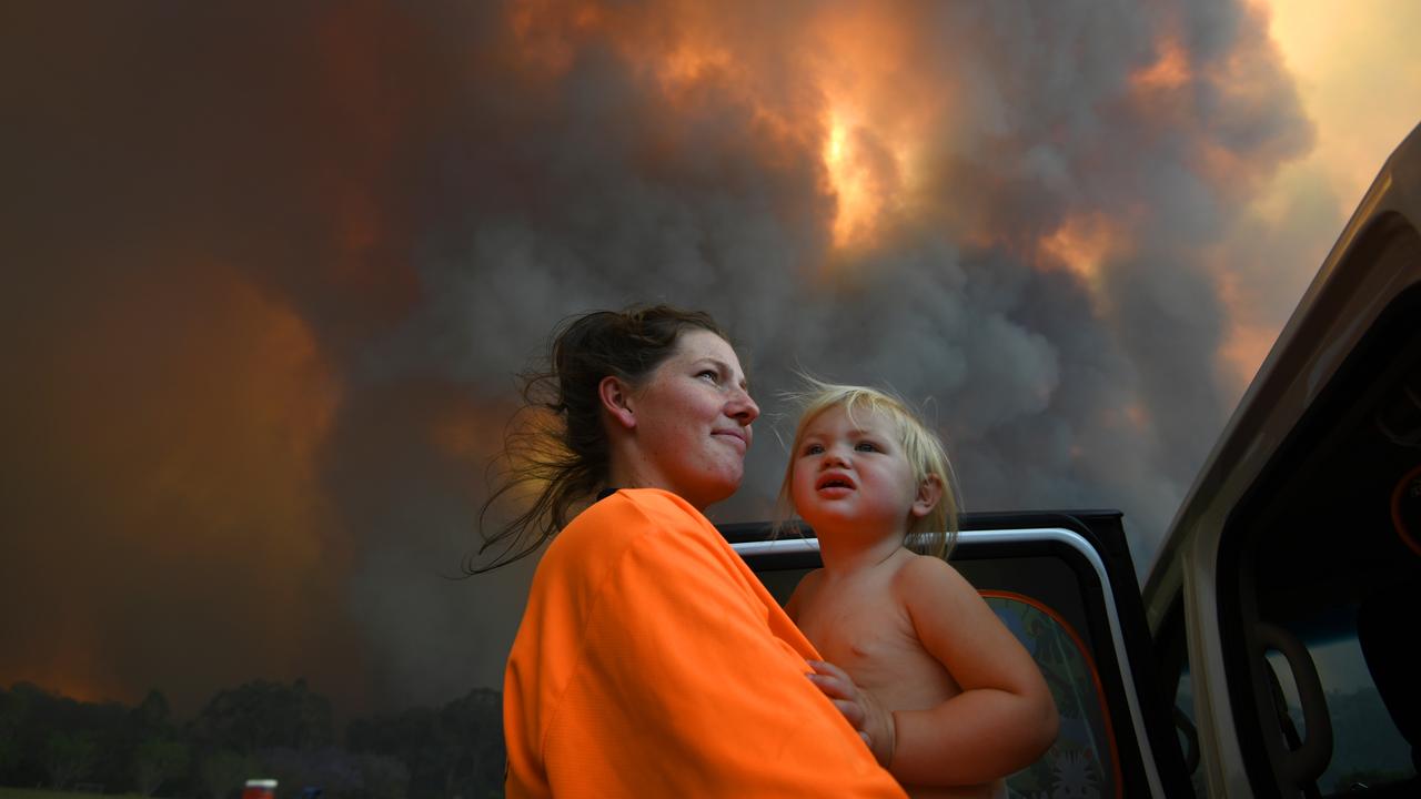 Sharnie Moren and her daughter Charlotte look on as thick smoke rises from bushfires at Nana Glen, near Coffs Harbour. Picture: AAP