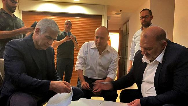 Head of the Arab Israeli Islamic conservative party Raam Mansour Abbas (R) signing a coalition agreement with Israel's opposition leader Yair Lapid (L) and right-wing nationalist tech millionaire Naftali Bennett in Ramat Gan near the coastal city of Tel Aviv on June 2.