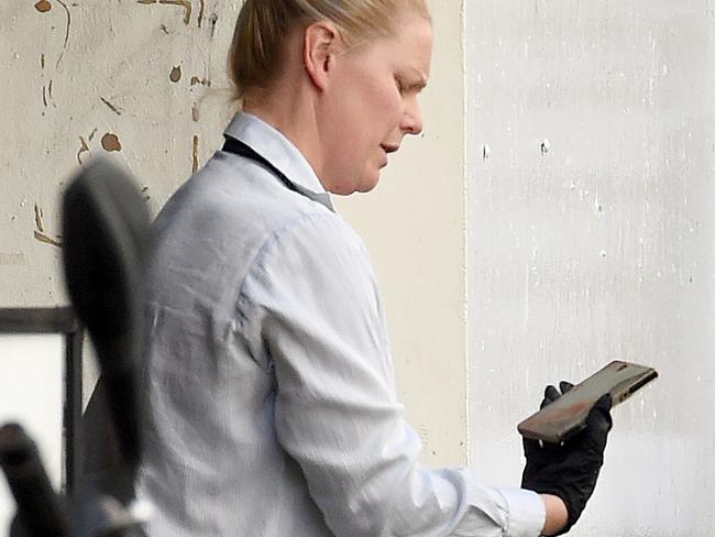 Police put a mobile phone in an evidence bag as they investigate after a man was fatally stabbed in the Golden Square Car Park in Little Bourke Street, China Town Melbourne. Picture: Nicole Garmston