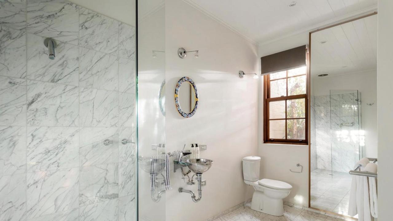 A marble-tiled bathroom with garden outlook and premium fixtures complements the home’s refined period character.