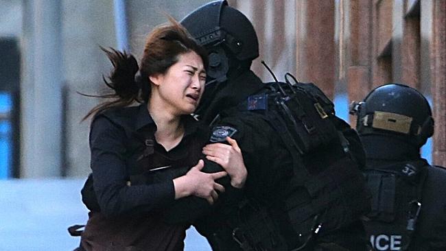 A hostage runs to armed tactical response police officers as she escapes from a cafe under siege at Martin Place. Picture: AP