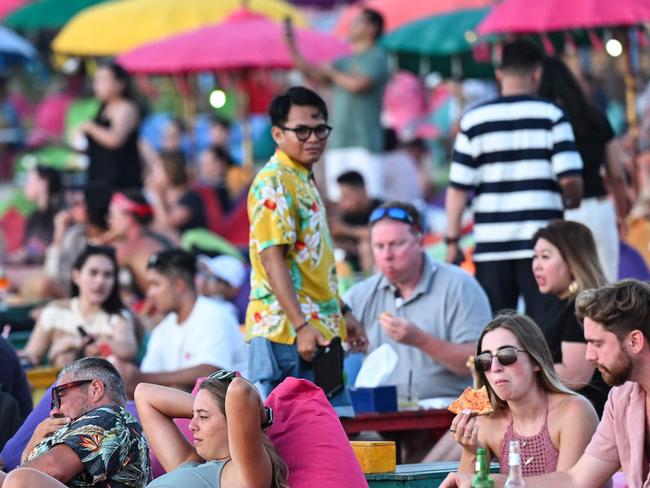 Foreign tourists relax on the Kuta Beach near Denpasar on Indonesia's resort island of Bali on November 18, 2023. (Photo by SONNY TUMBELAKA / AFP)