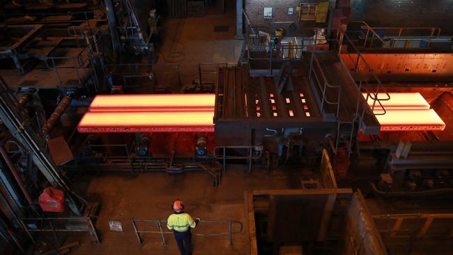 A worker watches as slabs of molten metal are cut to length at the slabcaster at BlueScope Steel manufacturing plant in Port Kembla. Picture: John Feder