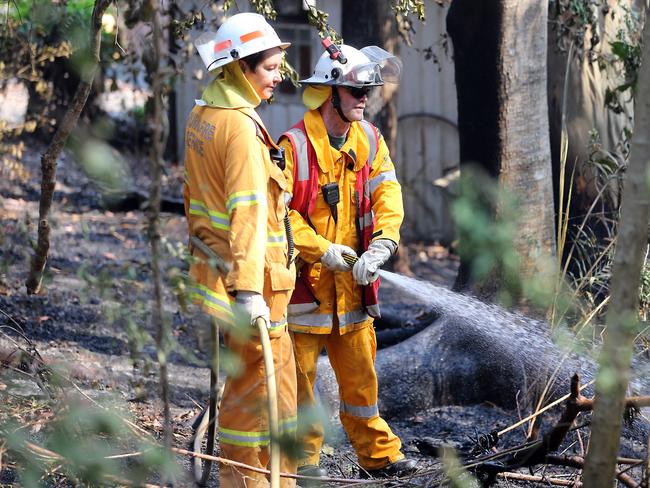 Dampening down the fire zone at Lower Beechmont in the Gold Coast hinterland yesterday. Picture: Richard Gosling/AAP