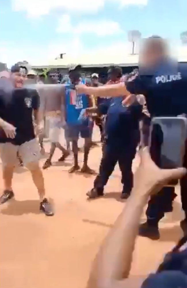 An officer appears to use a pepper spray against a person in the crowd.