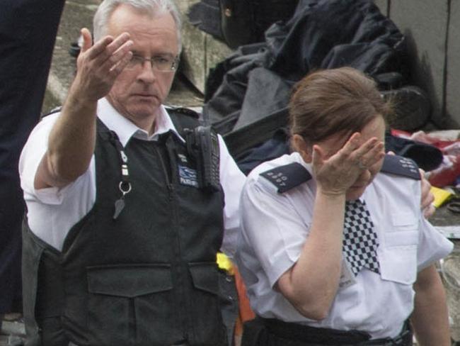 A police officer is led away by a colleague at the scene outside the Palace of Westminster, London where a suspected terrorist attack left five dead, including an unarmed police contestable. Picture: Stefan Rousseau/PA via AP.