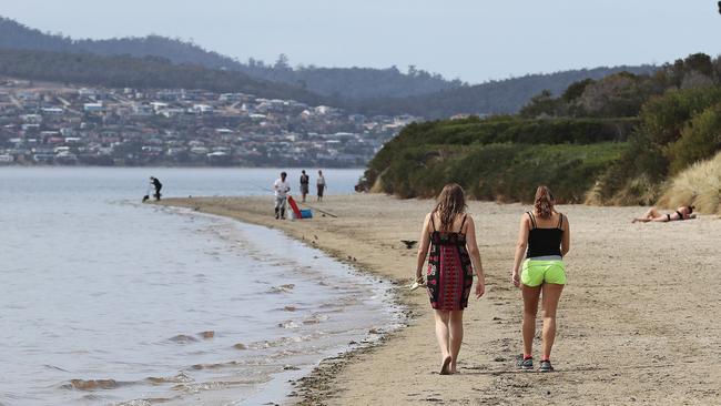 People walking along Nutgrove Beach in Sandy Bay. Picture: LUKE BOWDEN