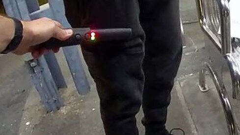 A Queensland Police metal detecting wand being used on a member of the public.