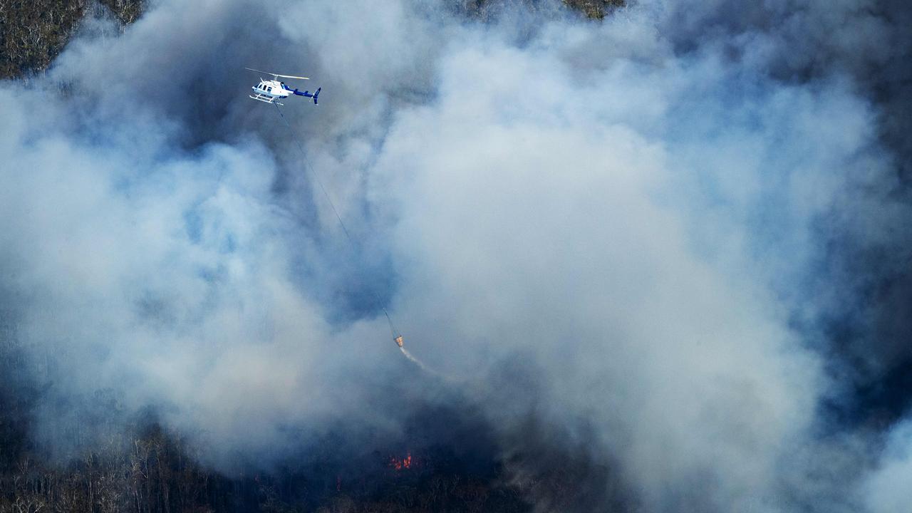 Water bombing Helicopter tackles the thick smoke of an out of control bushfire travelling from Peregian Beach towards Weyba Downs. Photo Lachie Millard