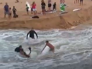 Surfers and beachgoers rescue a man swept away by the powerful current as water rushed from the entrance to Dee Why Lagoon into the ocean at Long Reef Beach on February 23, 2022. Image: Instagram - skykmonkey5.