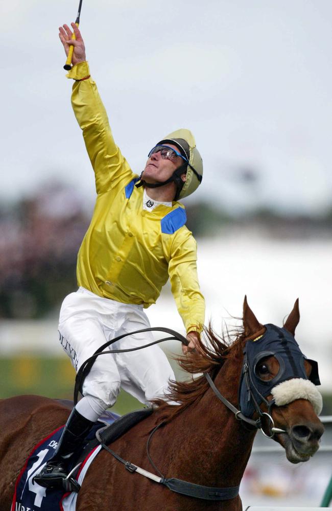 2002: Jockey Damian Oliver points to the heavens in tribute to his brother Jason, after winning the Melbourne Cup on Media Puzzle. Jason, also a jockey, died a week earlier after a race fall. Picture: Michael Dodge