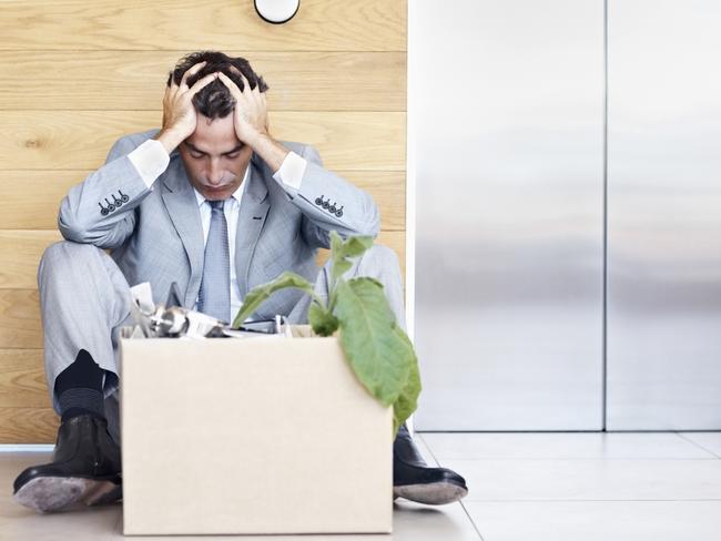 Portrait of a depressed manager sitting with head in hands as he waits for an elevator