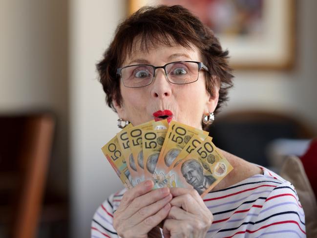 Woman with a surprised expression holding a fan of A$50  notes. Australian money generic banking