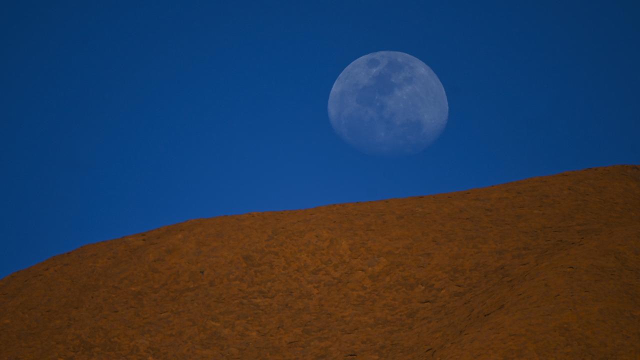 The moon is seen rising over Uluru, also known as Ayers Rock at Uluru-Kata Tjuta National Park in the Northern Territory. Picture: AAP/Lukas Coch