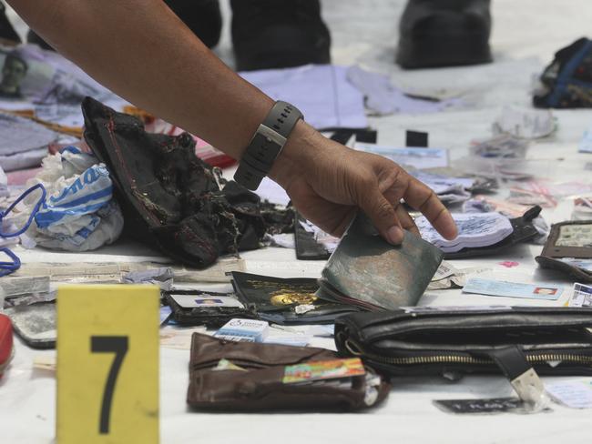 A police officer examines personal belongings recovered from the area where a Lion Air plane is suspected to have crashed, at Tanjung Priok Port in Jakarta, Indonesia, Tuesday, Oct. 30, 2018. Search and rescue personnel worked through the night to find victims of the Lion Air plane crash in Indonesia. (AP Photo/Binsar Bakkara)