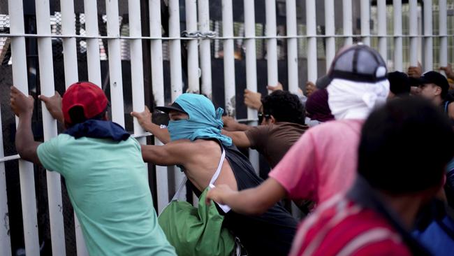 Central American migrants try to force their way through a customs gate at the border bridge connecting Guatemala and Mexico. Picture: A new group of migrants, who called themselves a second caravan, gathered on a bridge after forcing their way through a gate at the Guatemalan end and clashed with Mexican authorities. Picture: Billy Santiago/AP