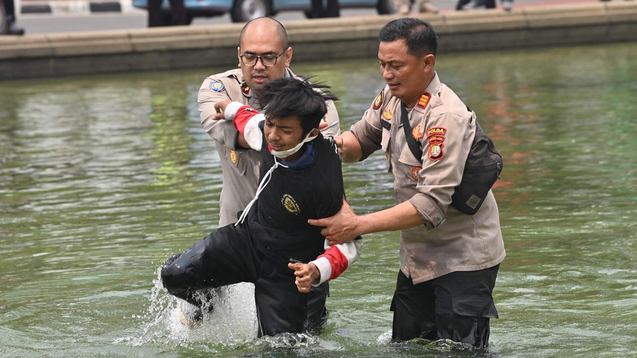 Police arrest a protester who climbed a fountain near the presidential palace. Picture: ADEK BERRY / AFP