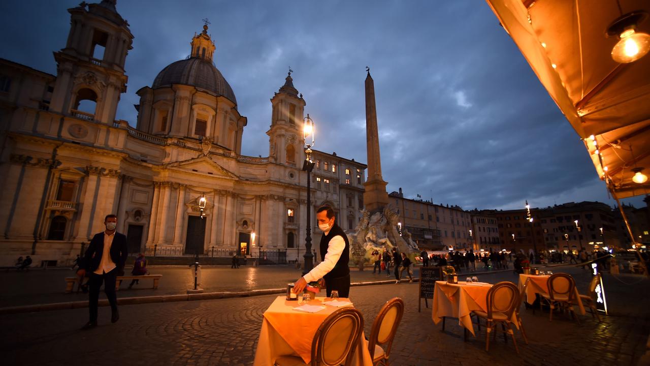 An employee cleans up a table on an empty terrace at Piazza Navona square before a night-time virus curfew entered into force in the Lazio region as a measure against the spread. Picture: Filippo Monteforte