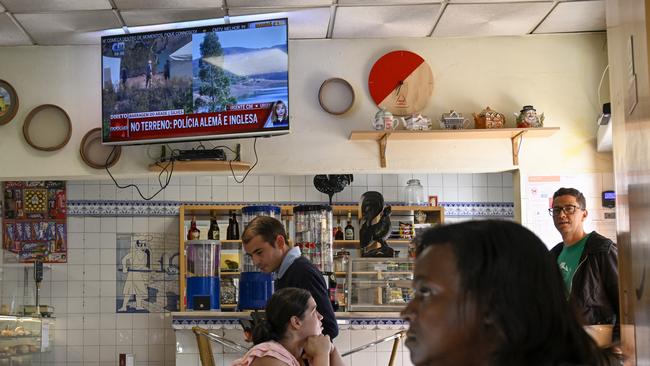 Locals in a shop near the search site as a TV screen shows images of the third day of the search for remains of Madeleine McCann this week. Picture: AFP