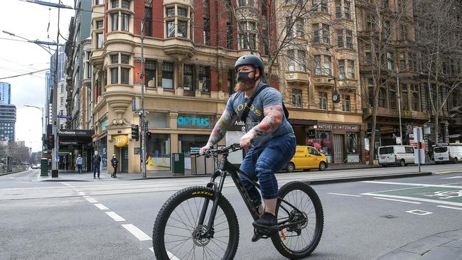 A cyclist rides down a quiet Collins Street in Melbourne. Picture: NCA NewsWire / Ian Currie