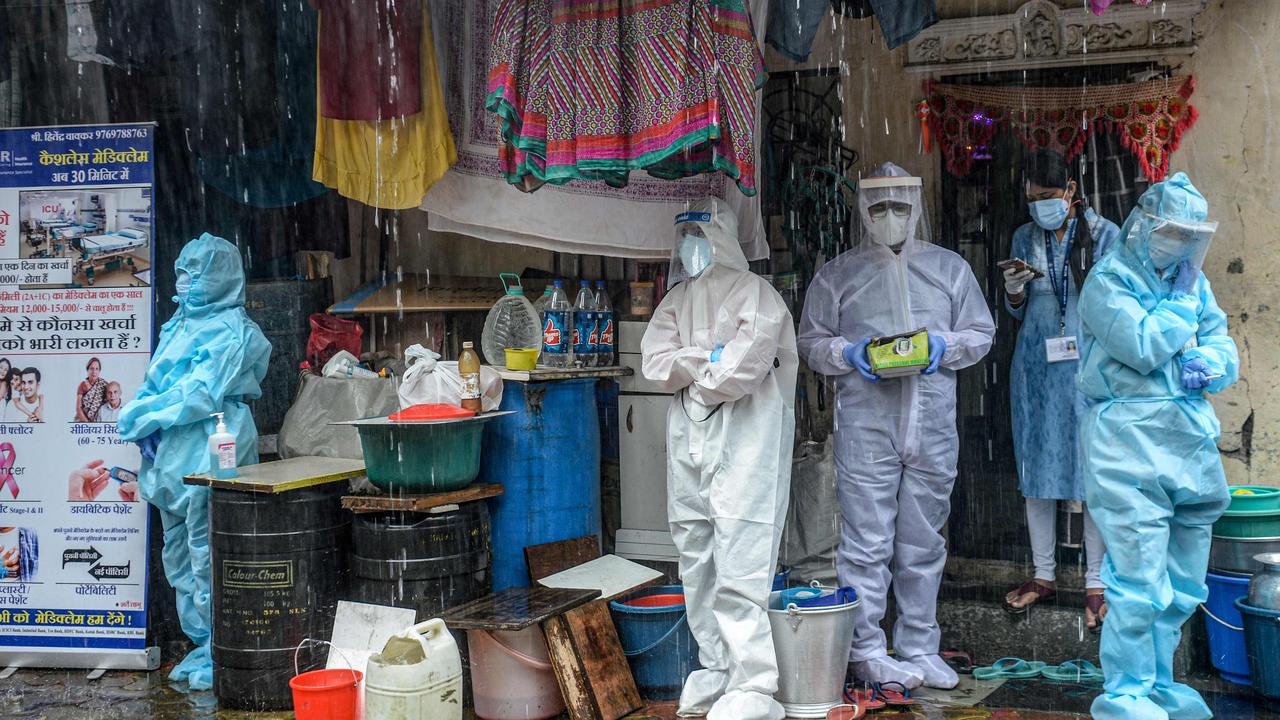 Health workers wearing PPE suits take shelter while conducting a COVID-19 coronavirus screening under heavy rain in Mumbai on August 12, 2020. Wearing PPE incorrectly has caused thousands of healthcare workers to come down with the disease. Picture: Indranil Mukherjee / AFP