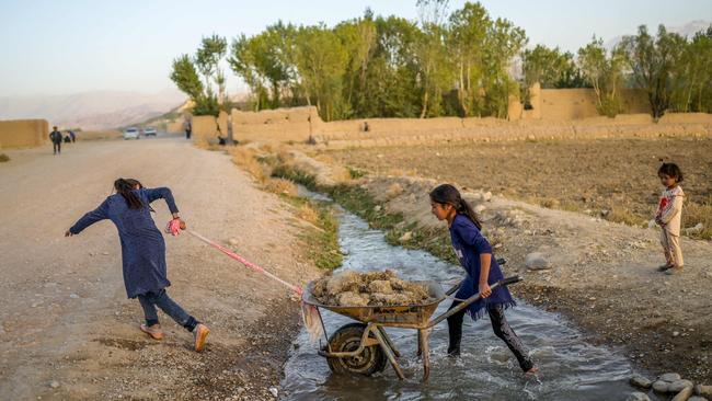 Girls push and pull a wheelbarrow near their village in Bamiyan. Picture: AFP