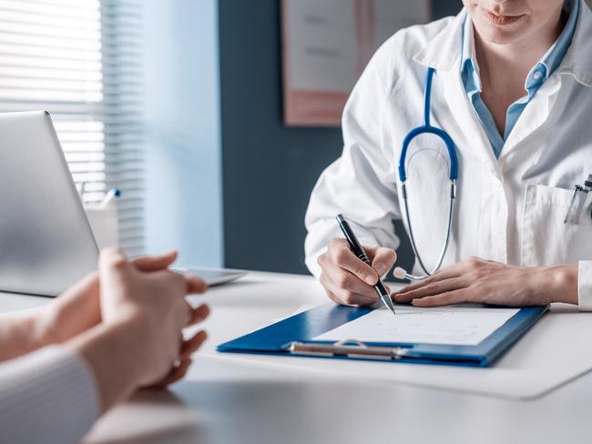 Doctor sitting at desk and writing a prescription for her patient