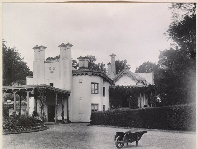 Photograph of Adelaide Cottage, in the Home Park, Windsor. A porch extends out from one part of the cottage and a wheelbarrow stands in the doorway. Picture: Picture: Supplied.