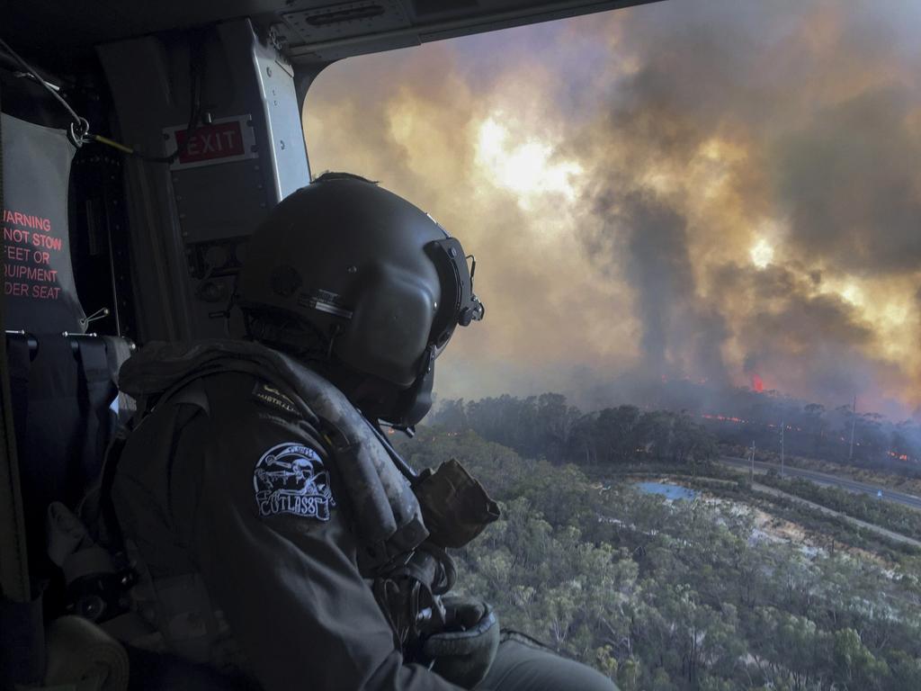 Royal Australian Navy Aircrewman, Petty Officer Jason Wickman assesses the Grose Valley bushfire in the Blue Mountains National Park during a sortie on an 808 Squadron MRH90 Taipan Military Support Helicopter. Picture: ADF