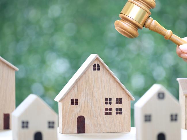 Property auction, Woman hand holding gavel wooden and model house on natural green background, lawyer of home real estate and ownership property concept