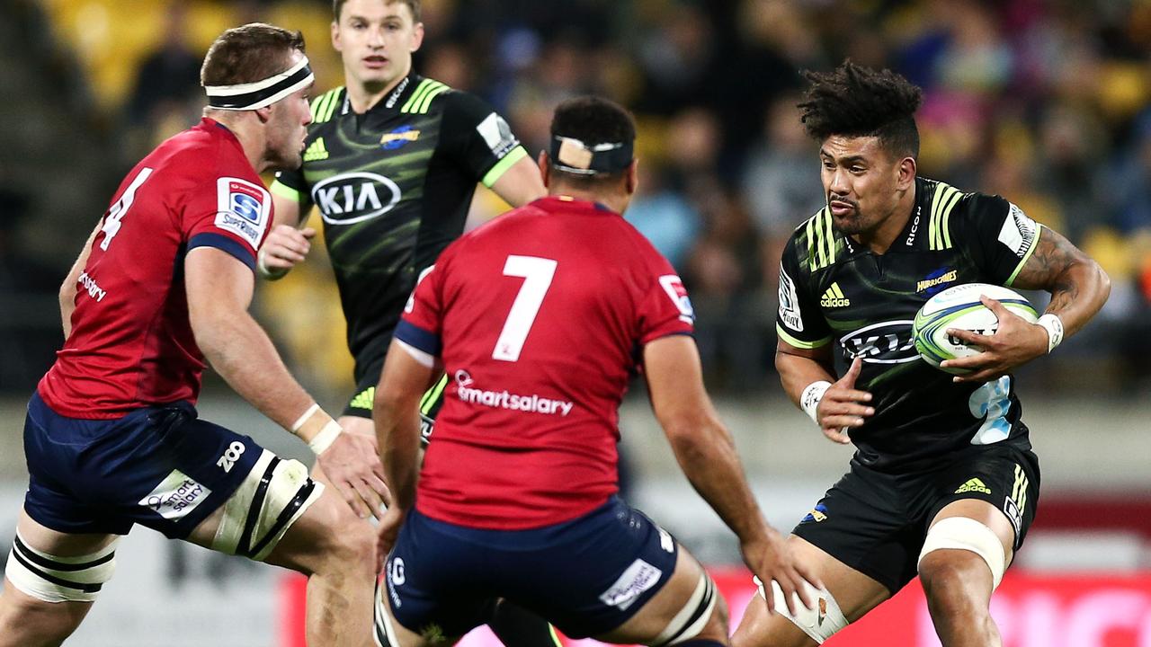 Ardie Savea of the Hurricanes runs at George Smith (right) and Izack Rodda of the Reds on Friday night.