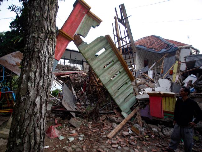 A man stands beside houses destroyed by the quake. Picture; AFP.