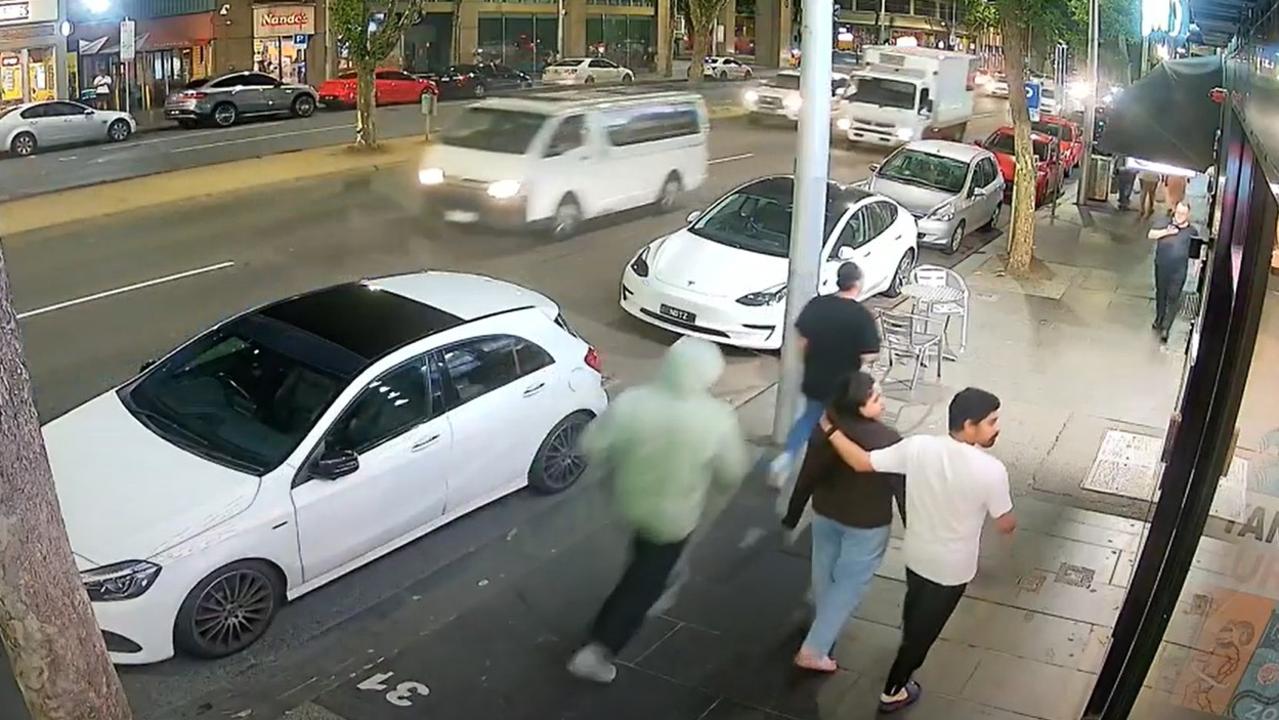 The man in the green jacket is seen running up to the unsuspecting pedestrian. Picture: Supplied