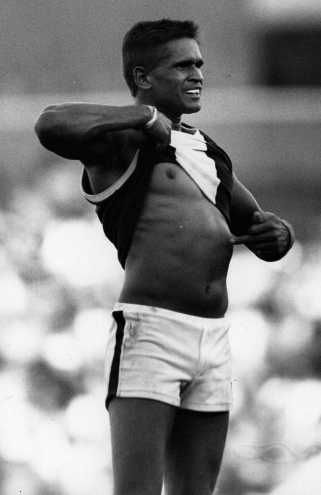 Nicky Winmar lifts his jumper and points to the colour of skin