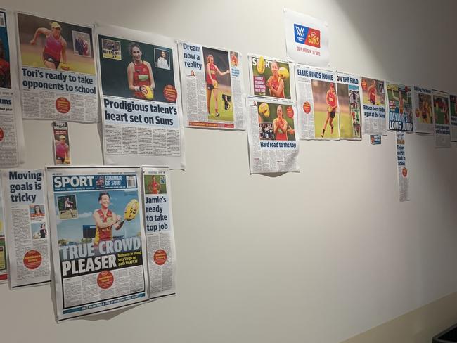 Gold Coast Suns players putting Gold Coast Bulletin newspapers up on their walls.