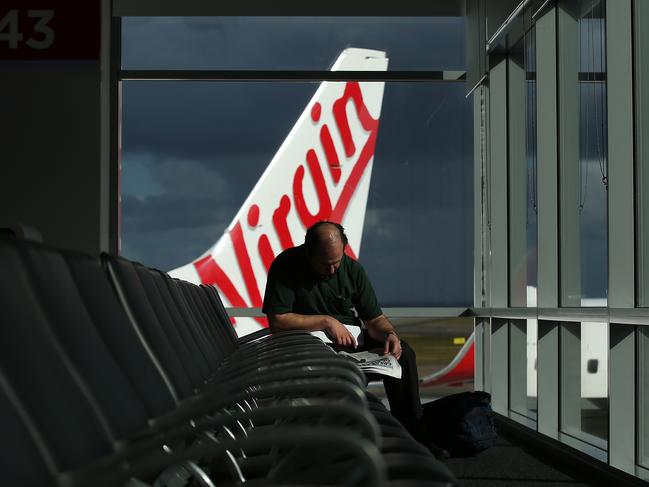 Bloomberg Photo Service 'Best of the Week': A passenger reads a newspaper in a departure lounge as a Virgin Australia Holdings Ltd. aircraft stands on the tarmac at the domestic terminal at Sydney Airport in Sydney, Australia, on Wednesday, Aug. 27, 2014. Virgin Australia, the nation's second-largest carrier, is scheduled to report full-year results on Aug. 29. Photographer: Brendon Thorne/Bloomberg