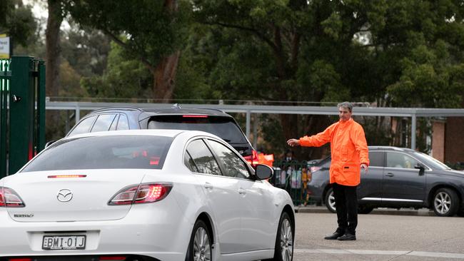 Traffic outside Carlingford West Public School which has begun surveillance on parents and uses teachers (pictured) to direct traffic to deal with the pickup hour. Picture: Jonathan Ng