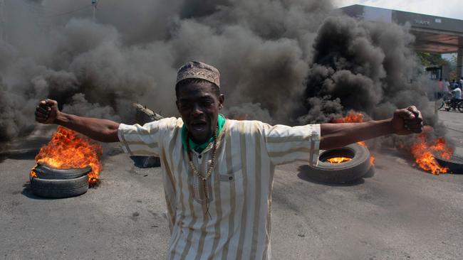 A protester reacts while tires burn in the street during a demonstration following the resignation of its Prime Minister Ariel Henry, in Port-au-Prince, Haiti.